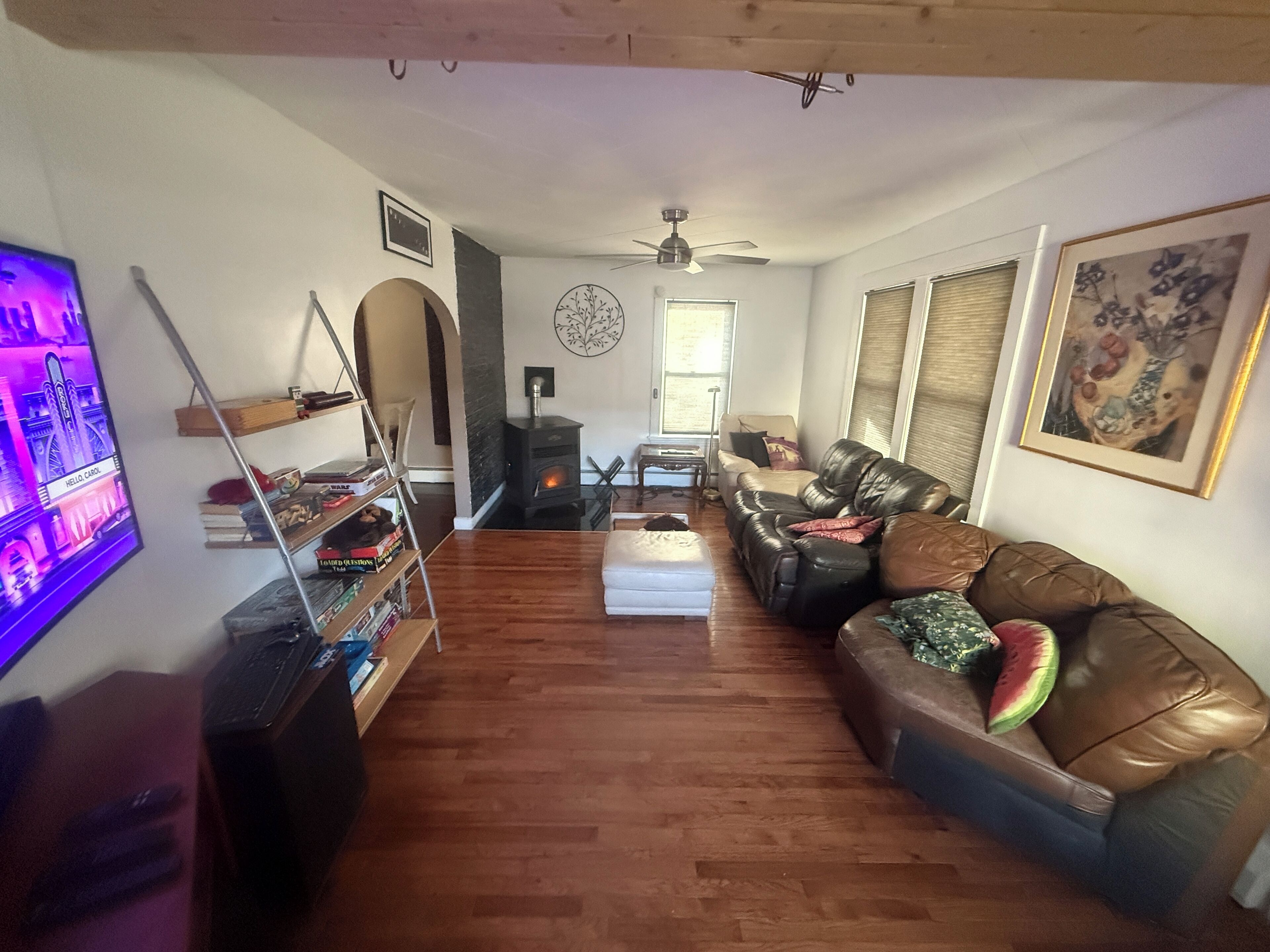 Ein gemütliches Wohnzimmer mit Kamin, Ledersofa, Holzboden und einem Fernseher auf der linken Seite.