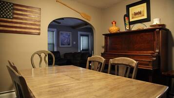 A dining area with a wooden table and chairs, an American flag, a wooden spoon, and a framed picture on the wall.