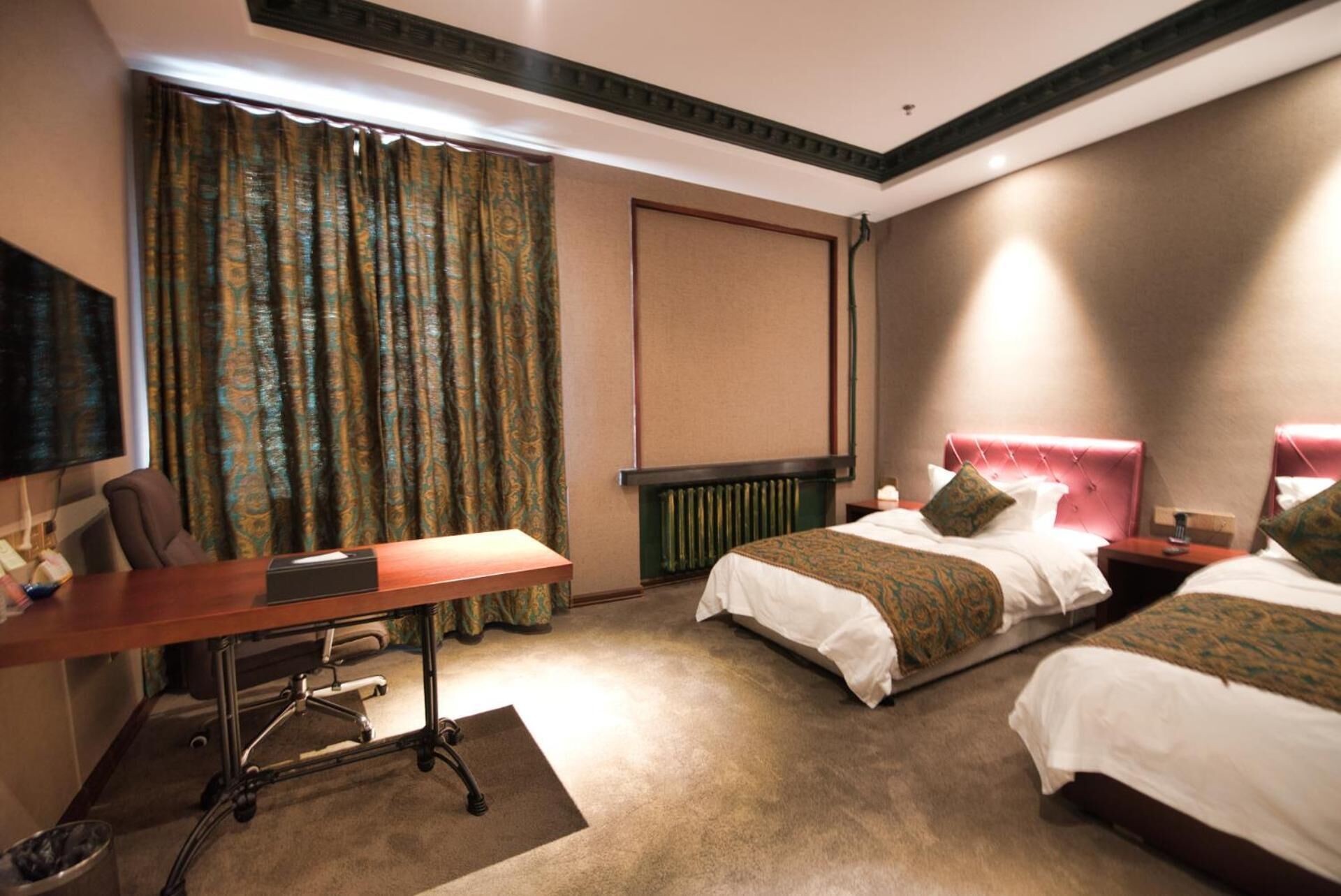 Habitación de hotel con dos camas, un escritorio, una silla, un televisor y una ventana con cortinas.