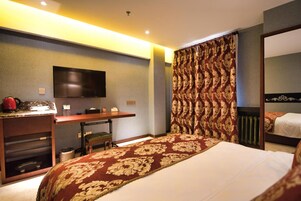 Una habitación de hotel con cama, escritorio, televisión y cortina estampada.