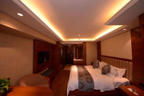 A hotel room with a large bed, a TV, a desk, and a chair. - Bremen Hotel Harbin Train station (Harbin)