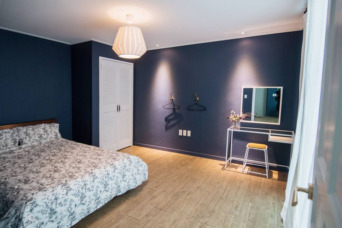 Ein Schlafzimmer mit einem Bett, einem Schminktisch, einem Spiegel und einer Hängeleuchte.