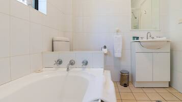 A modern bathroom with a bathtub, toilet, sink, and mirror.