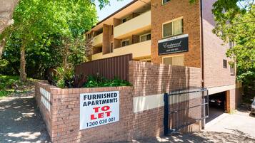 A multi-story apartment building with a sign indicating furnished apartments for rent.