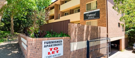 A multi-story apartment building with a sign indicating furnished apartments for rent.