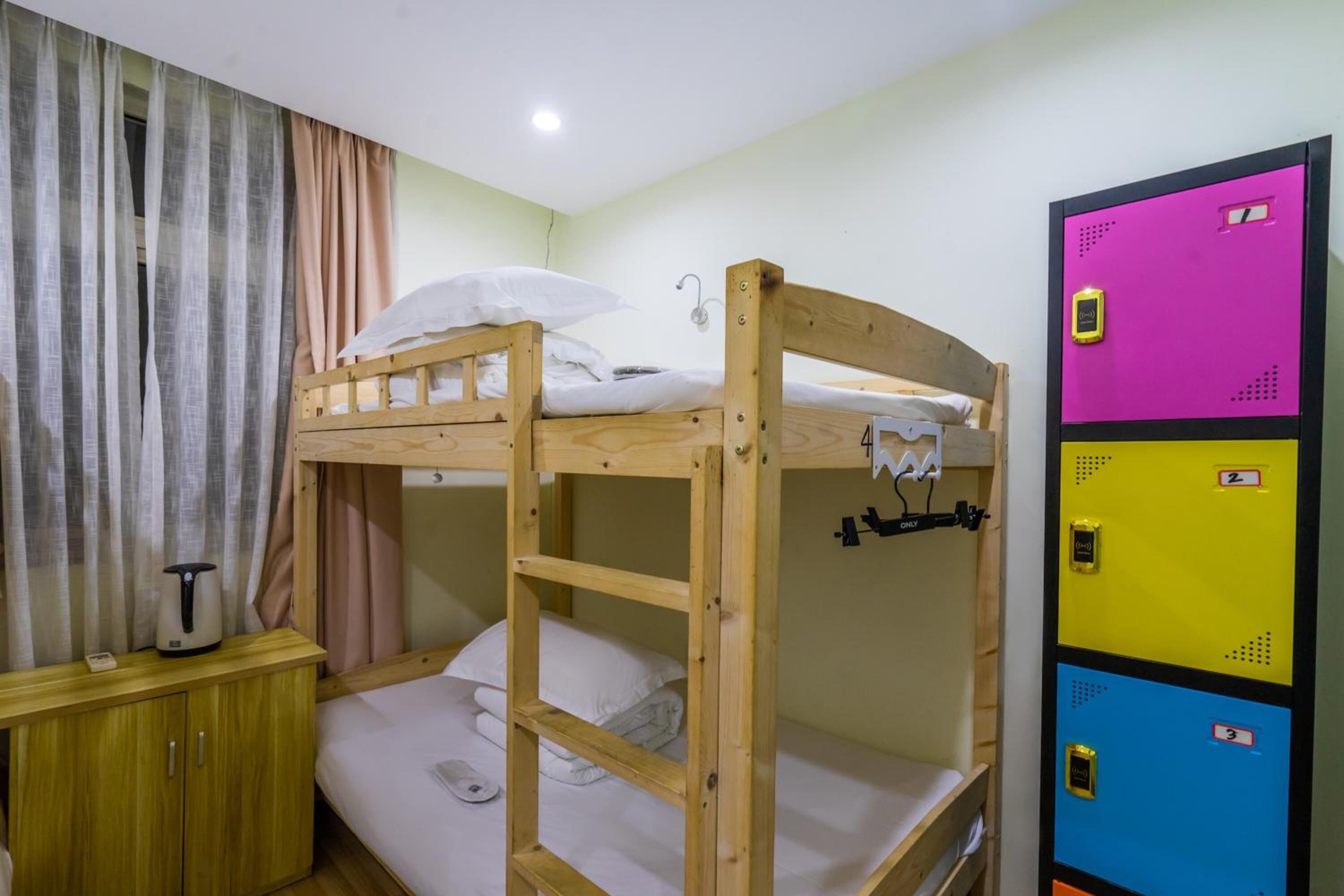 Habitación con literas de madera, un mueble pequeño de madera y un contenedor de almacenamiento colorido con compartimentos numerados.