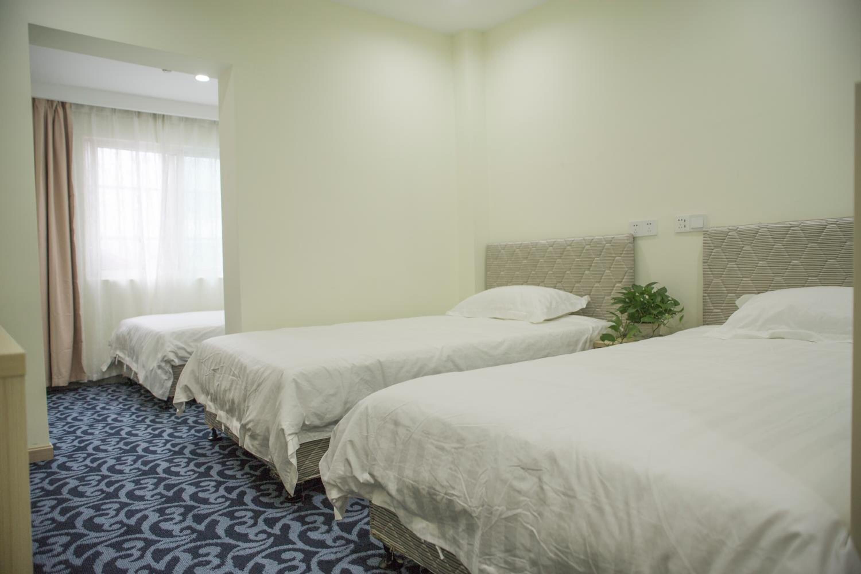 A hotel room with two single beds, a small desk, and a patterned carpet.