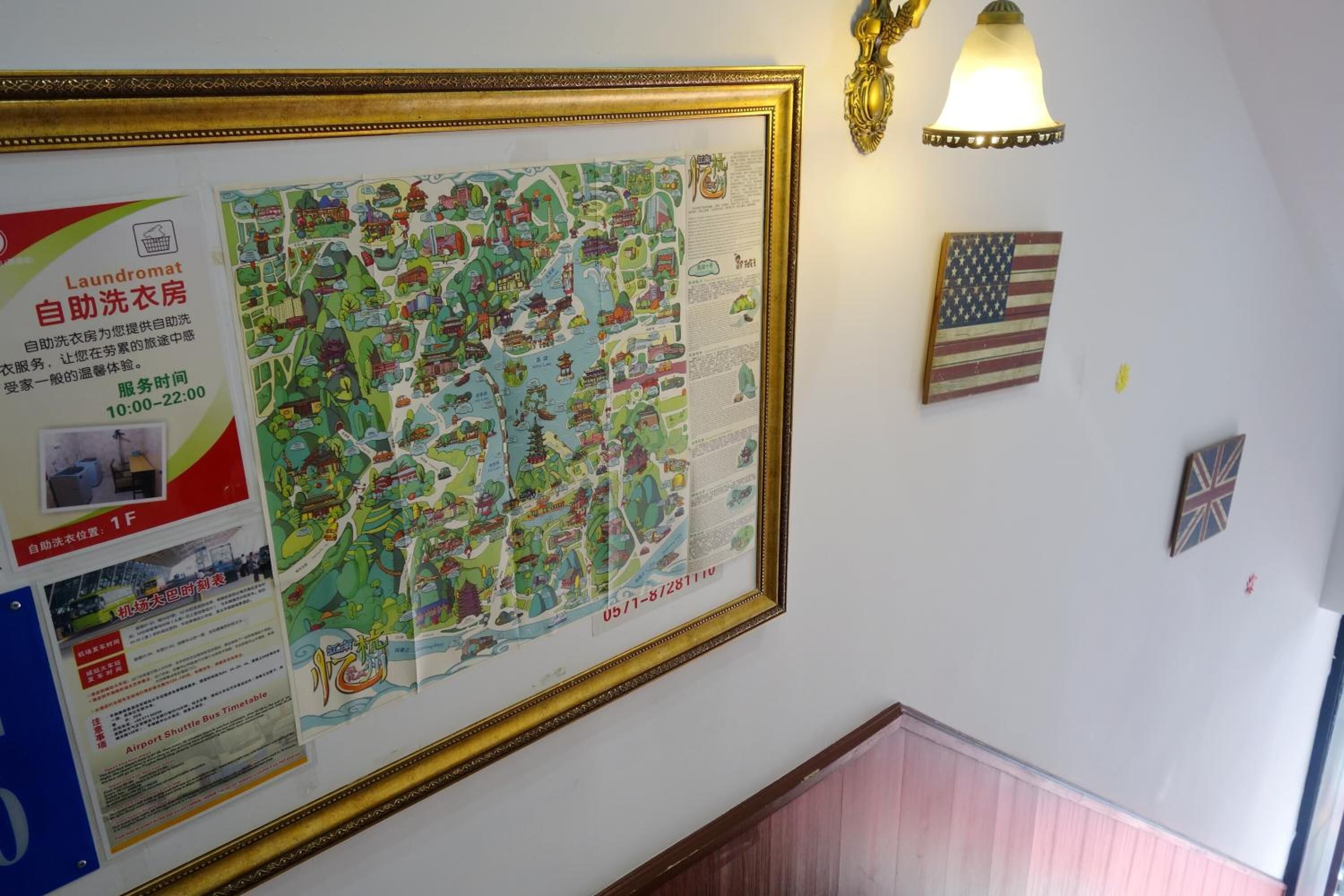 A wall with a framed map, a lamp, and two flags.
