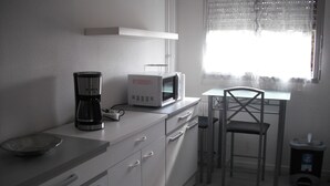 A kitchen with a coffee maker, microwave, and a dining area with a chair and table.