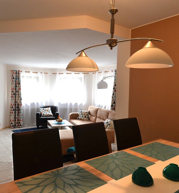 A dining area with a table set for four, a sofa, and a chair in the background.