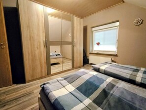 Ein Schlafzimmer mit Kleiderschrank, Bett und einem Fenster mit Jalousien.