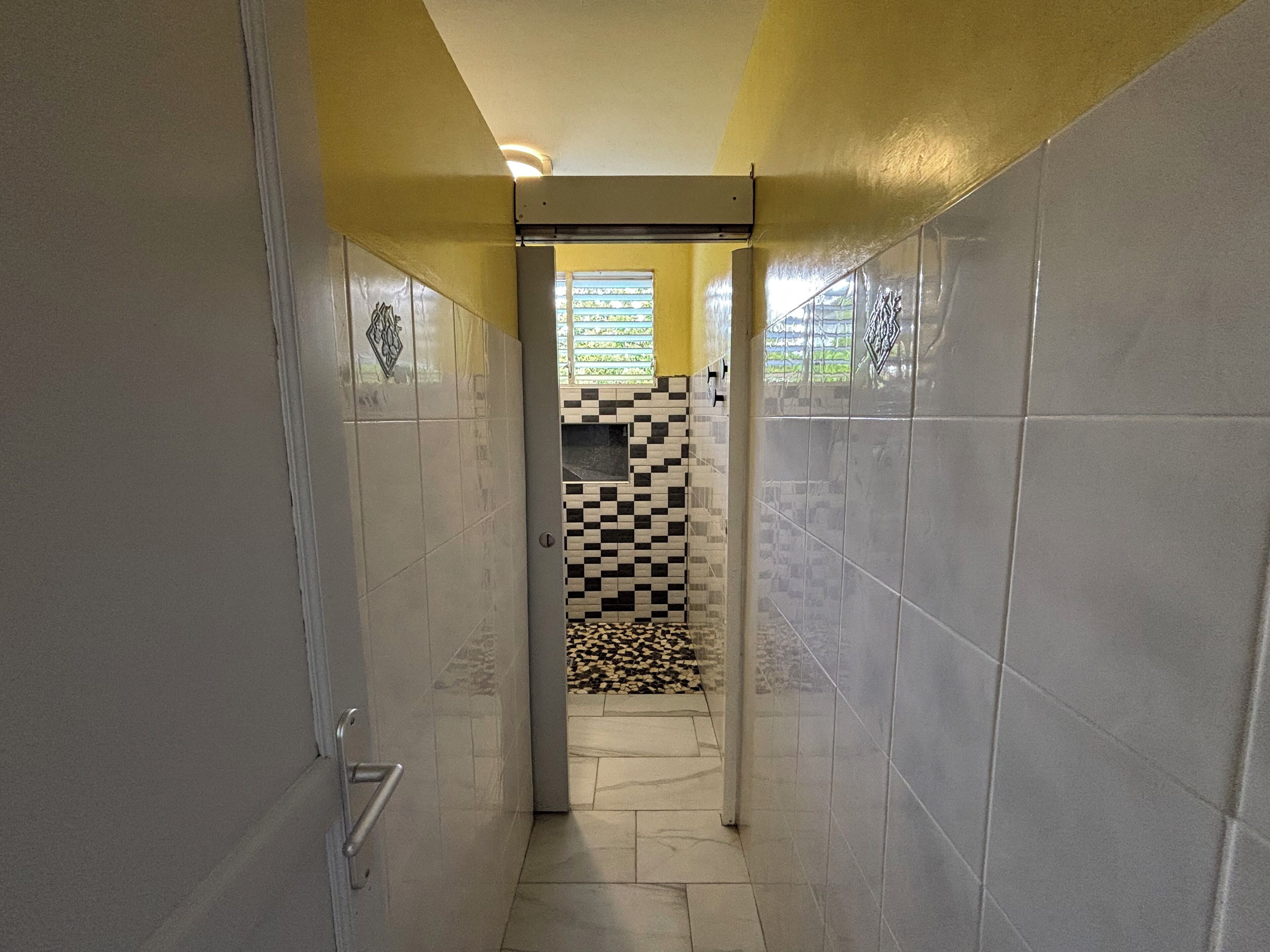 A narrow hallway with tiled walls and a checkered floor pattern.