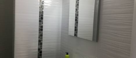 Un baño con un lavamanos blanco, un espejo y un dispensador de jabón verde.