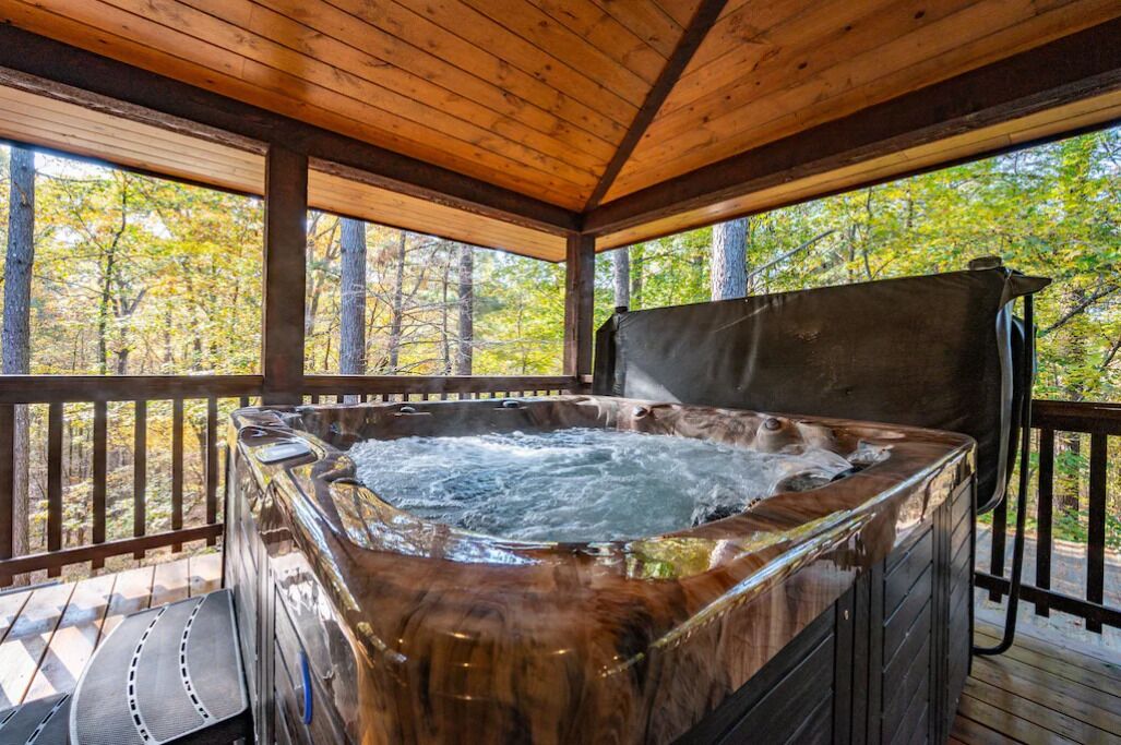 A hot tub on a wooden deck with a view of a forest.