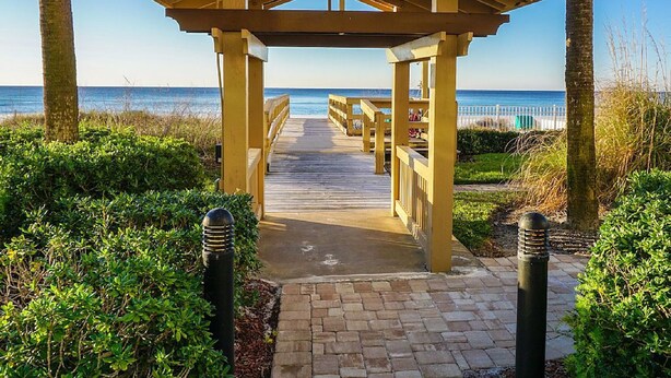 Una passerella di legno conduce a un padiglione sulla spiaggia, con vista sull'oceano.