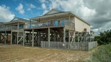 A two-story wooden house with a balcony, a porch, and a fenced yard.