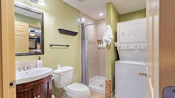 A bathroom with a sink, toilet, shower, and a built-in washer and dryer.