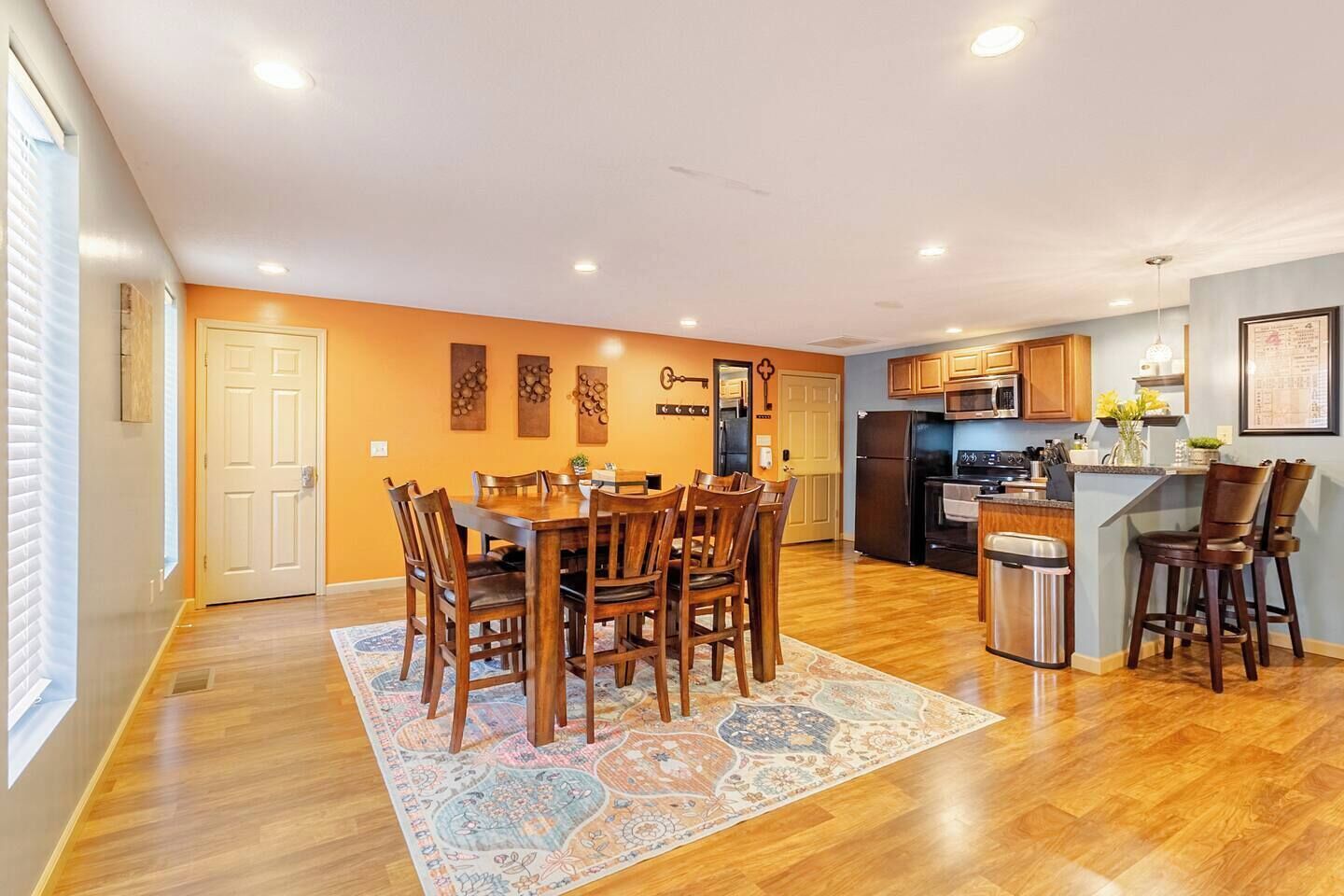 Una cocina amplia con armarios de madera, un refrigerador y un comedor con mesa y sillas.