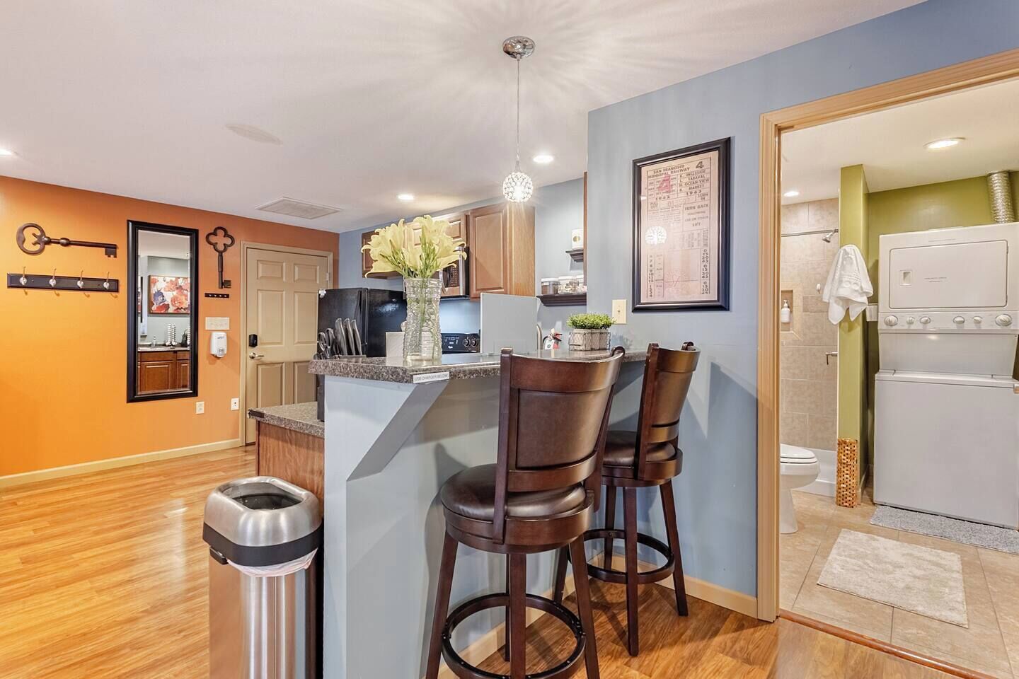 A modern kitchen with a bar area, wooden flooring, and a small island with bar stools.