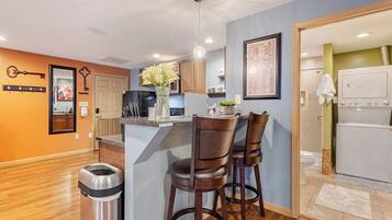 A modern kitchen with a bar area, wooden flooring, and a small island with bar stools.