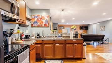 A modern kitchen with wooden cabinets, a large island, and a dining area with a black table.