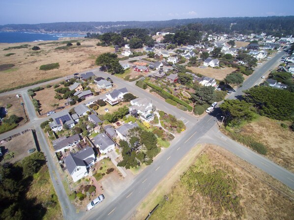 Vista aérea de uma área residencial com casas, ruas e uma linha costeira ao fundo.