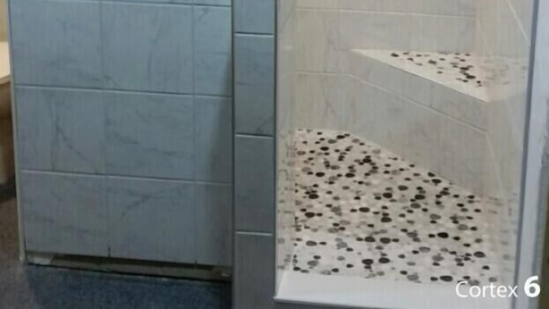 Eine Dusche mit Zickzack-Fliesenmuster, ein weißes Waschbecken und ein gefliester Boden.