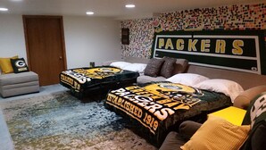 Ein Zimmer mit zwei Betten, einer Couch und einer Wand mit dem Packers-Logo.