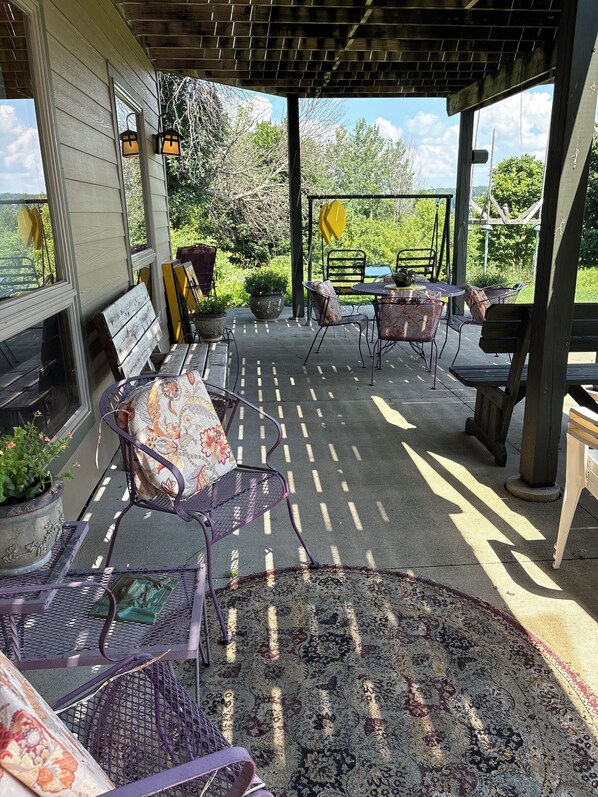 An outdoor patio with metal chairs and tables, surrounded by potted plants and a pergola structure. - Country setting 2-3 miles from the River, Luther College and downtown Decorah (Decorah)