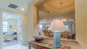 A dining area with a table set for two, a sailboat model, and a modern lamp. - January 2026 Still Available ! TREVISO BAY -RESORT. LUXURY POOL & Spa GOLF HOME (Naples)