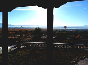 A view from a covered area with a pergola structure, overlooking a landscape with trees and distant mountains. - Secure carport, amazing Views and Reviews! Private suite with patio. (Albuquerque)
