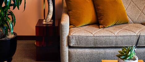 A sofa with two cushions, a potted plant, and a small table with a succulent.