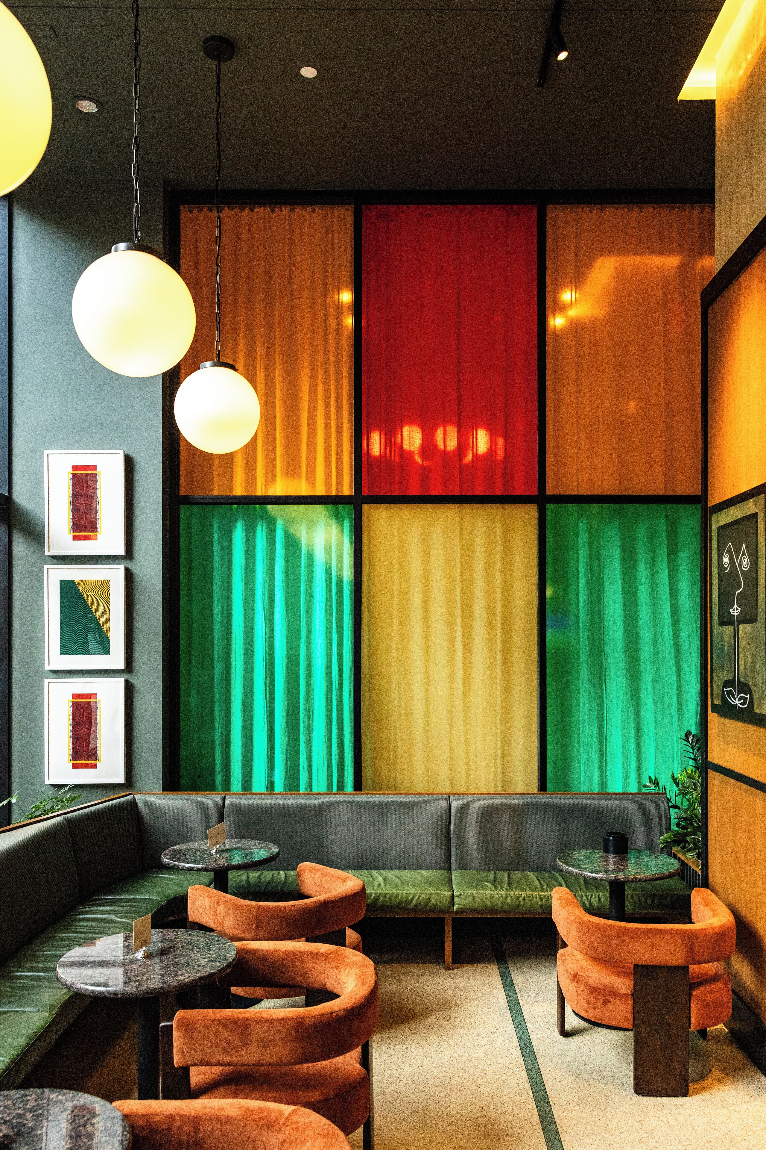 A modern interior with a green sofa, orange chairs, and a small table.