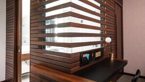 Habitación moderna con un panel divisor de madera, un escritorio con lámpara y vistas al exterior.