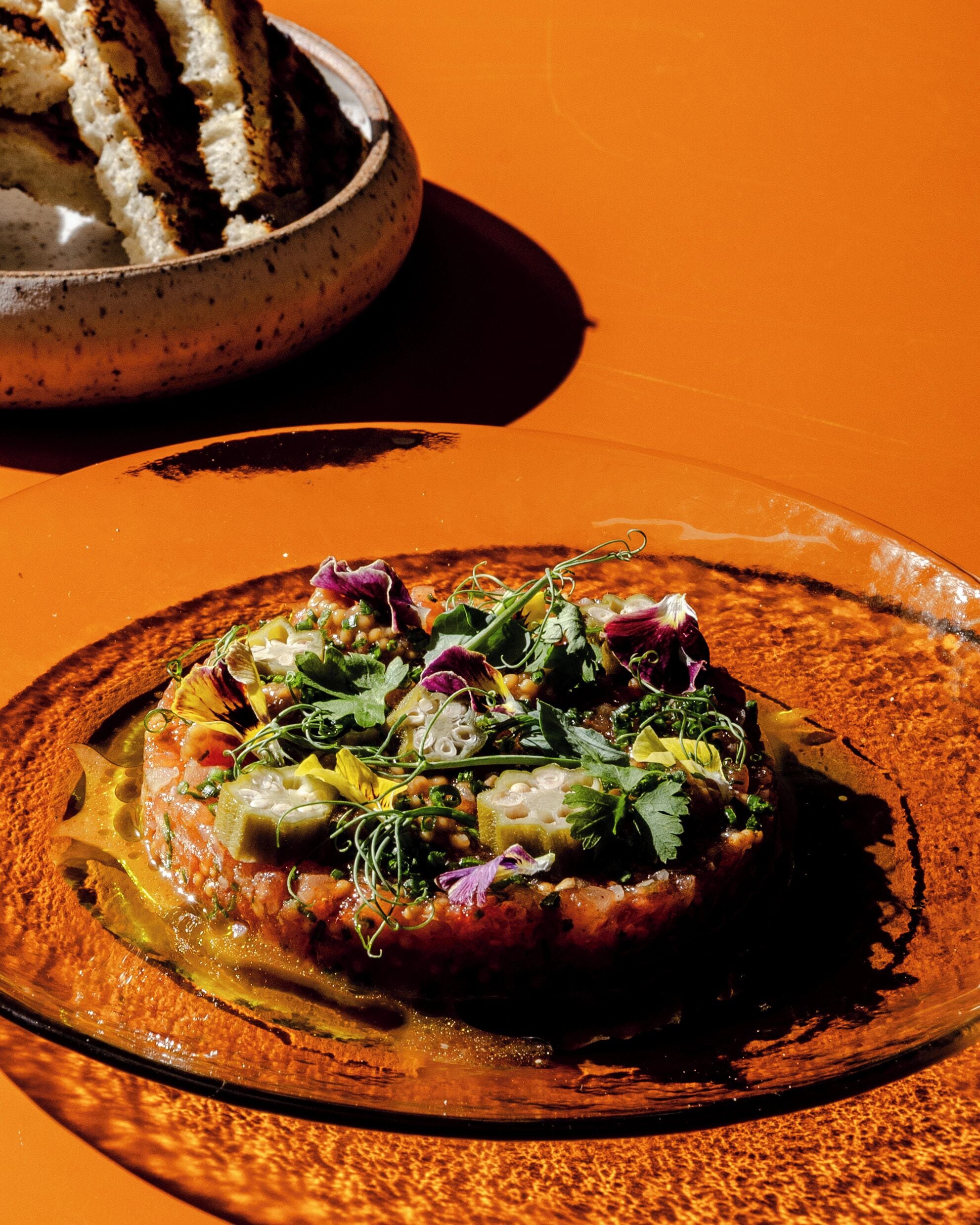 A plate of food with various vegetables and herbs on a textured orange table.