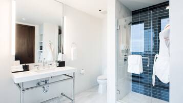 A modern bathroom with a glass-enclosed shower, a white sink, and a large mirror.