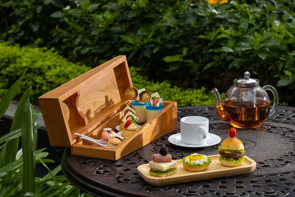 Uma caixa de madeira com diversos alimentos e um bule sobre uma mesa.