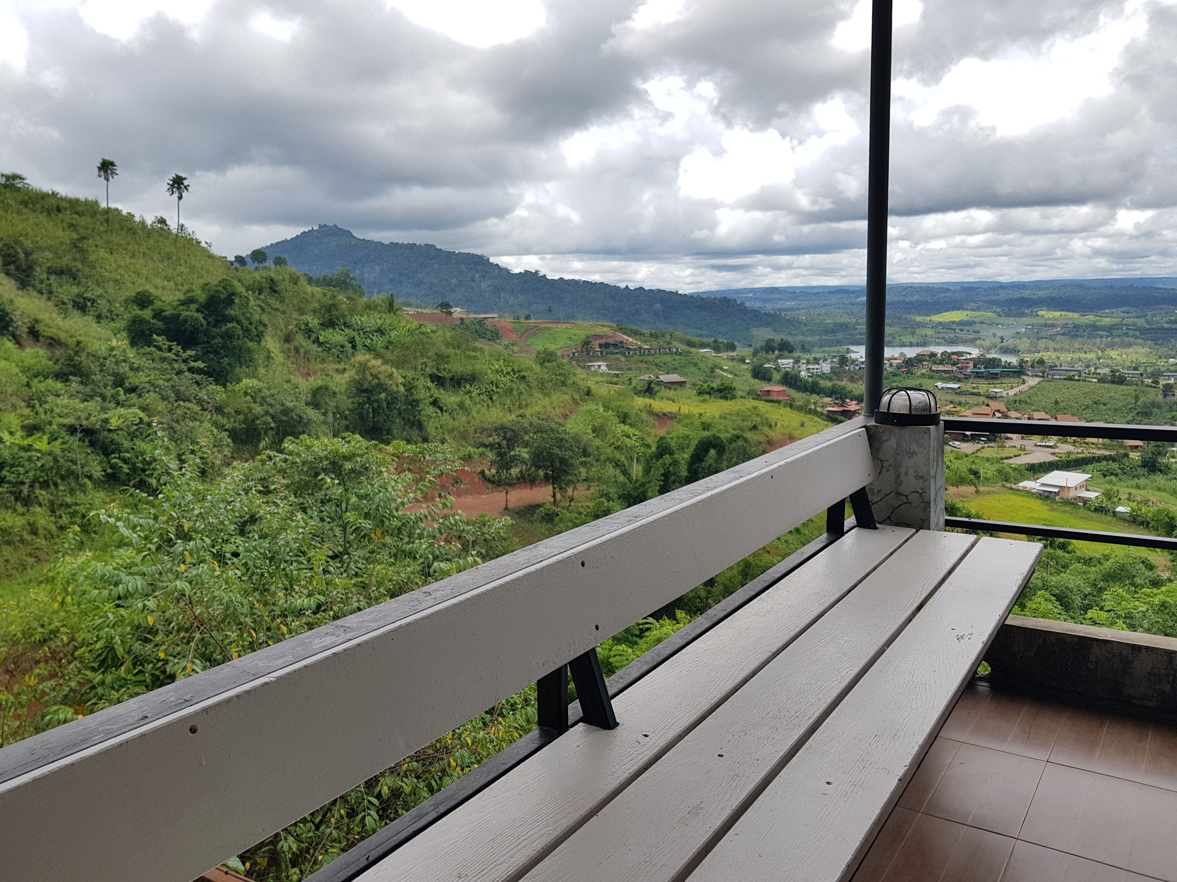 A bench overlooking a lush green landscape with hills and a river.