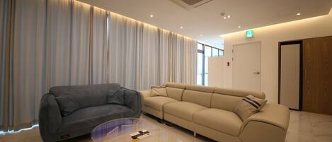A modern hotel lobby with a grey sofa, a beige sofa, and a clear glass coffee table.