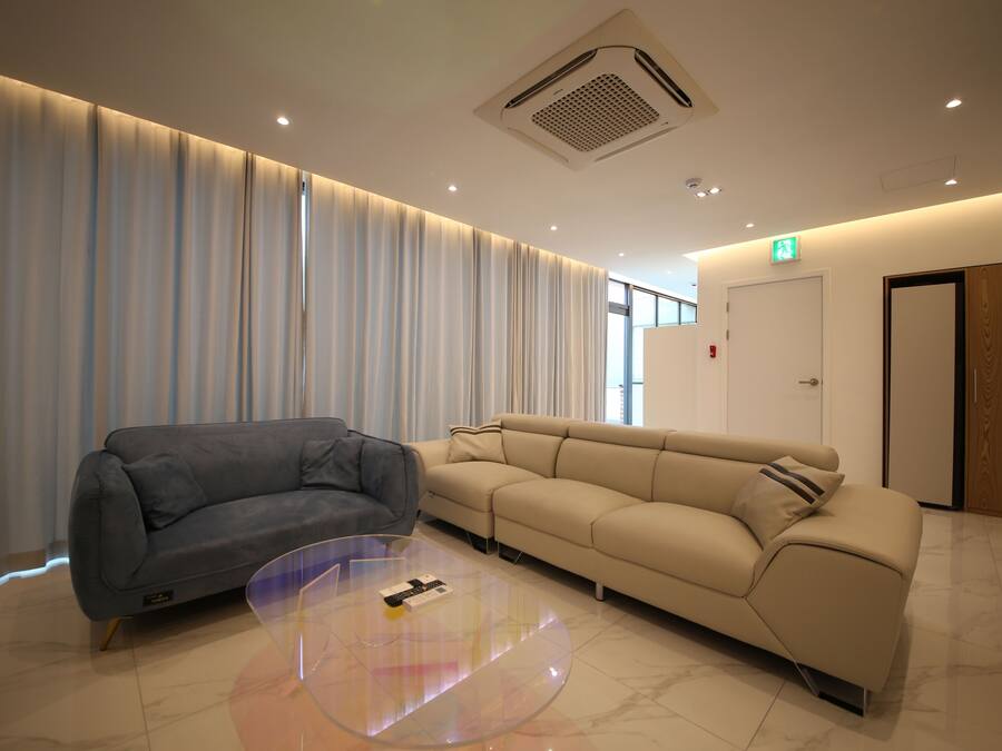 A modern hotel lobby with a grey sofa, a beige sofa, and a clear glass coffee table.