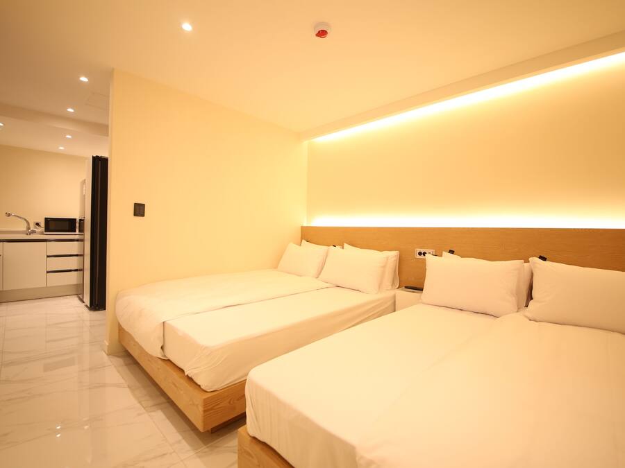 A hotel room with two beds, a kitchenette, and a bathroom.