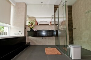 Ein modernes Badezimmer mit einem schwarzen Waschtisch, einer Duschkabine aus Glas und einer weißen Toilette.