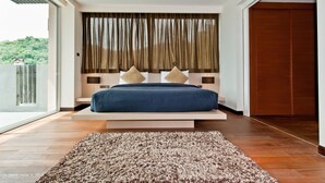 Un dormitorio moderno con una cama grande, vistas a zonas verdes y suelo de madera.