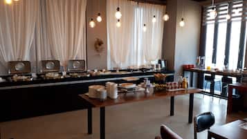 A breakfast buffet with various food items and a seating area with chairs and tables.