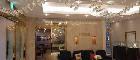 Un vestíbulo de hotel con mostrador de recepción, un sofá y una araña.