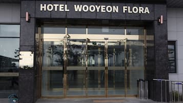 A entrada do Hotel Wooyheon Flora, com portas de vidro e uma visão clara do interior.