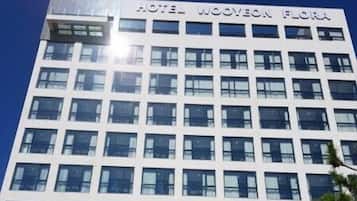 A modern hotel building with the name "Hotel Woven Flora" prominently displayed.