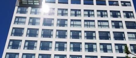 Un hôtel moderne dont le nom, « Hotel Woven Flora », est affiché en grand sur la façade.