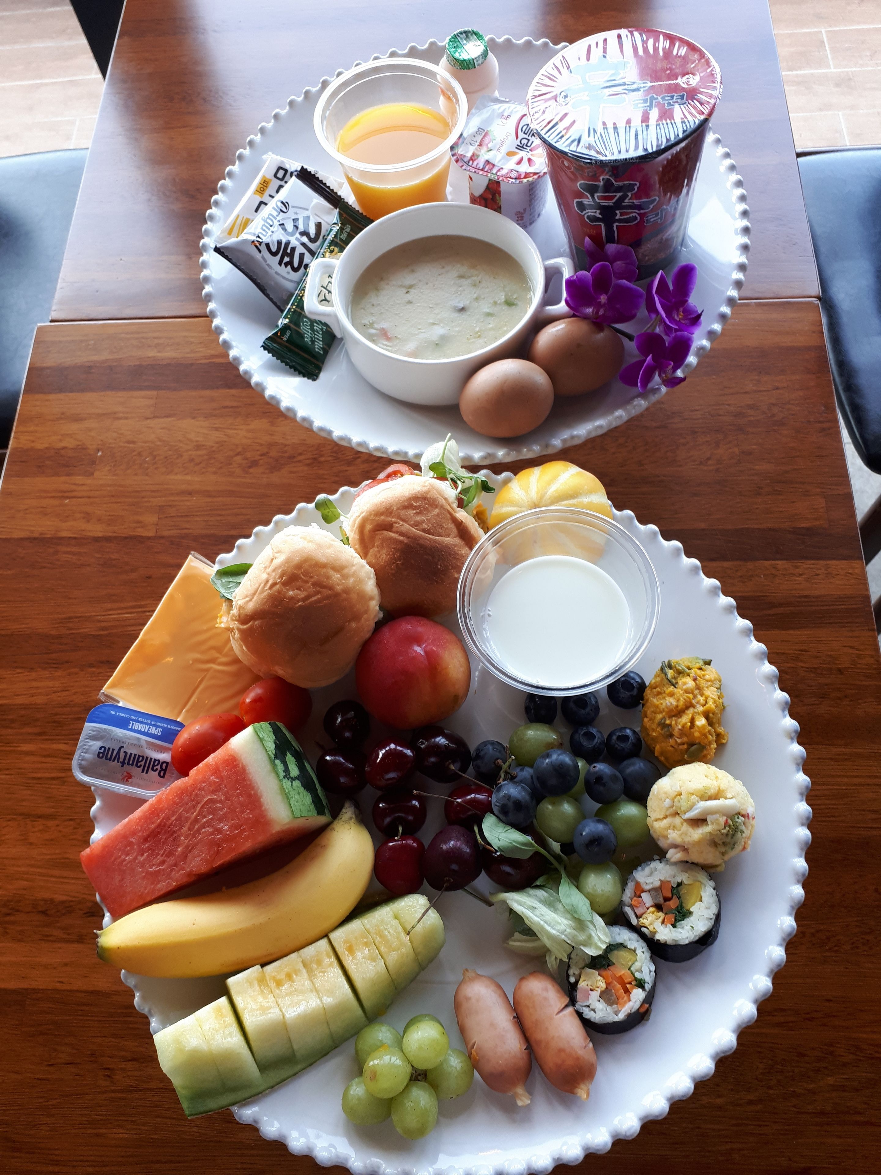 A breakfast tray with eggs, toast, fruit, yogurt, and a cup of soup.