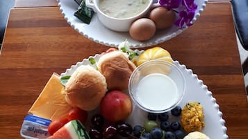 A breakfast tray with eggs, toast, fruit, yogurt, and a cup of soup.